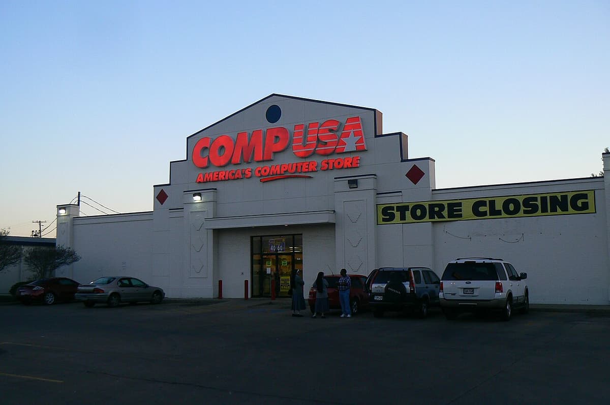 A CompUSA store at dusk with a yellow store closing banner