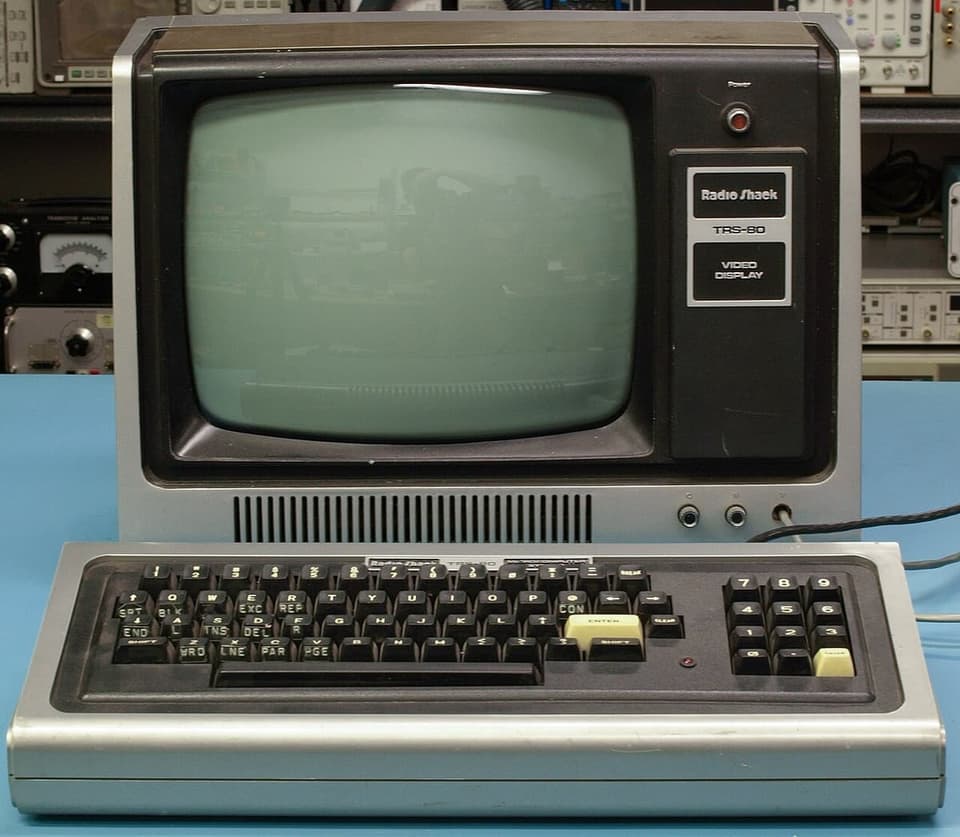 A TRS-80 Model I keyboard unit in front of its Radio Shack video display